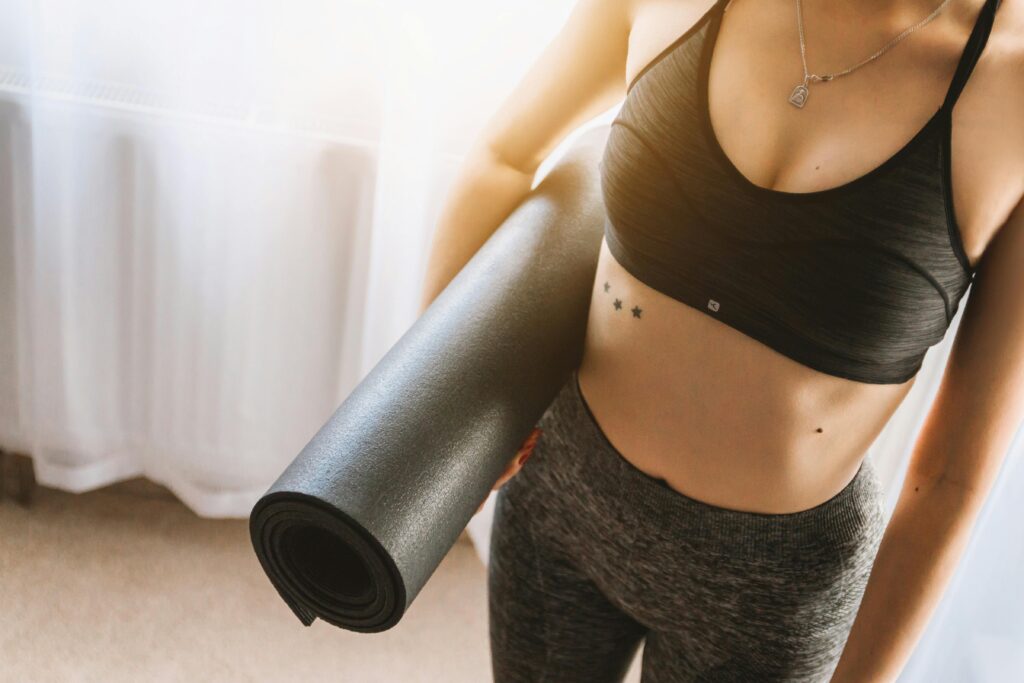 pexels-photo-834893-834893 Fit woman in active wear holding yoga mat indoors, ready for workout.